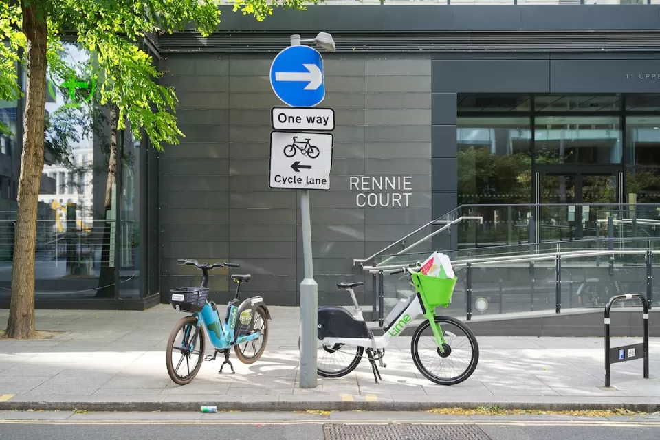 Two electric dockless bikes parked on sidewalk in London, UK.
